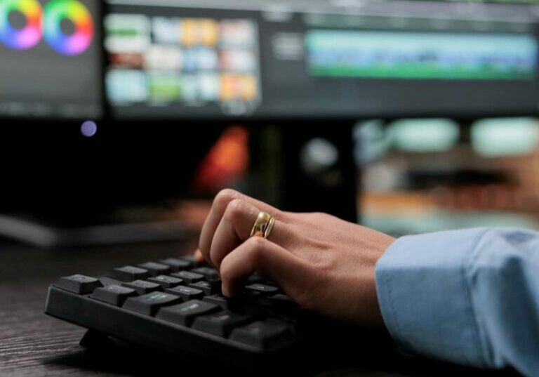 Close up shot of video graphic editor using specialized software to edit movie footage and improve visual quality. Professional videographer sitting at multi monitor workstation enhancing film frames.