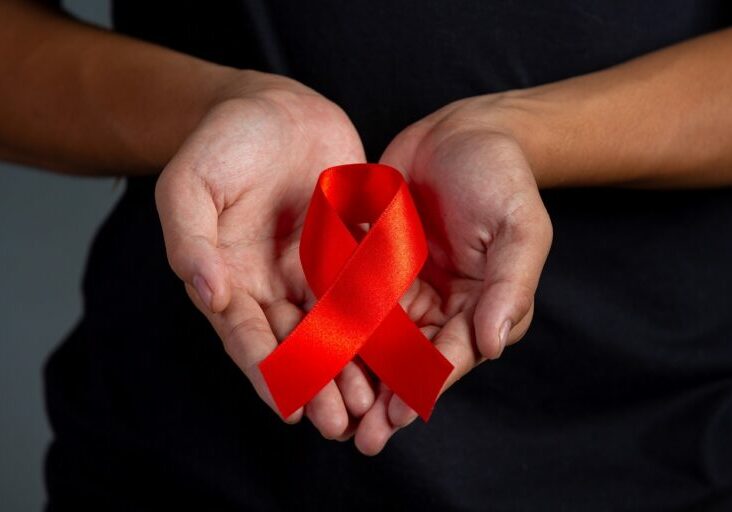 Woman hand holding red ribbon HIV awareness concept World AIDS Day and World Sexual Health Day.