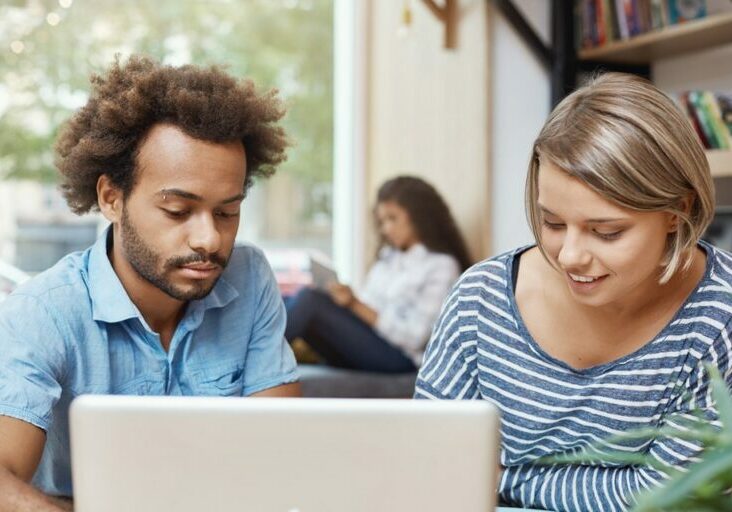 two-young-freelance-designers-sitting-co-working-space-looking-laptop-monitor-searching-new-ideas-furniture-designers-pair-young-cheerful-people-smiling-spending-morning-libra-1