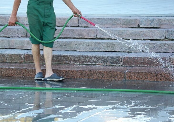 worker-from-hose-watering-city-street